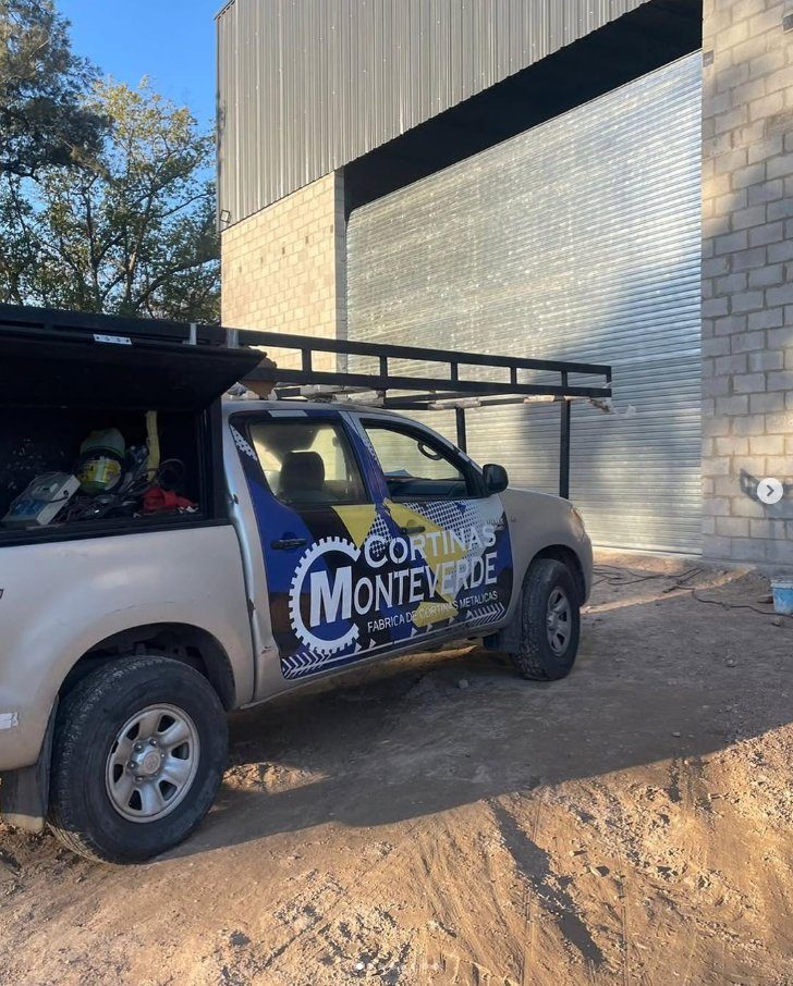 Camioneta de Cortinas Monteverde frente a una cortina metálica instalada en un galpón