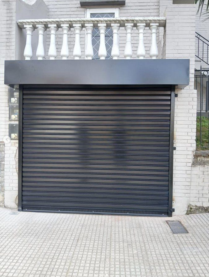 Cortina metálica negra con cajón en el frente de una casa